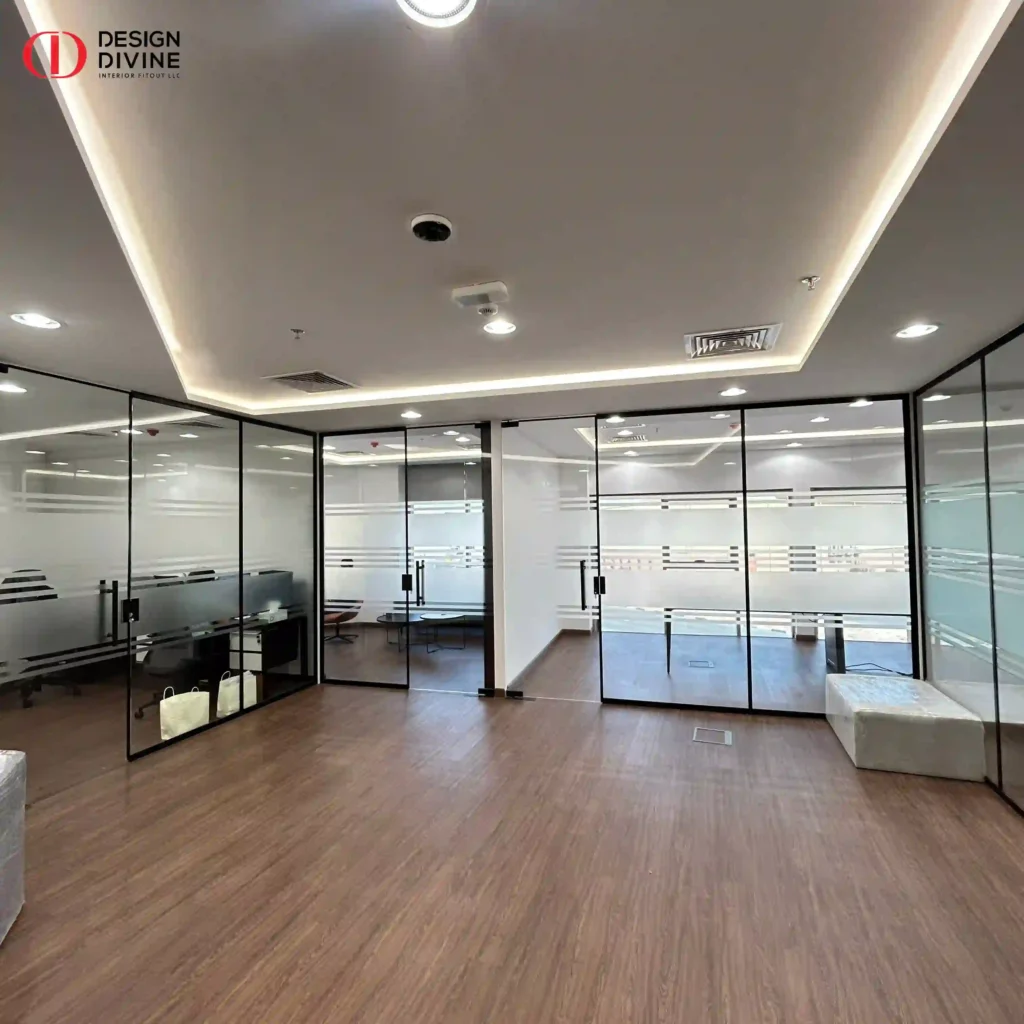 Open office with black-framed frosted glass partitions, LED cove ceiling and wood-effect flooring, ITEX office fitout in Dubai